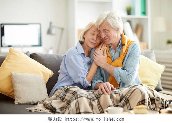 有爱心的老夫妇温柔地坐在舒适的沙发上晚年幸福幸福的人微笑的老人